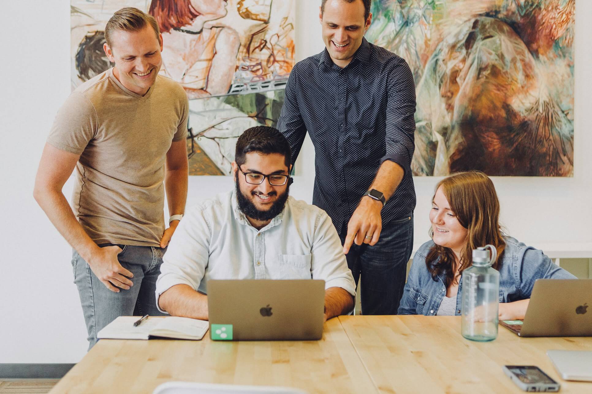 Team of colleagues collaborating around laptop
